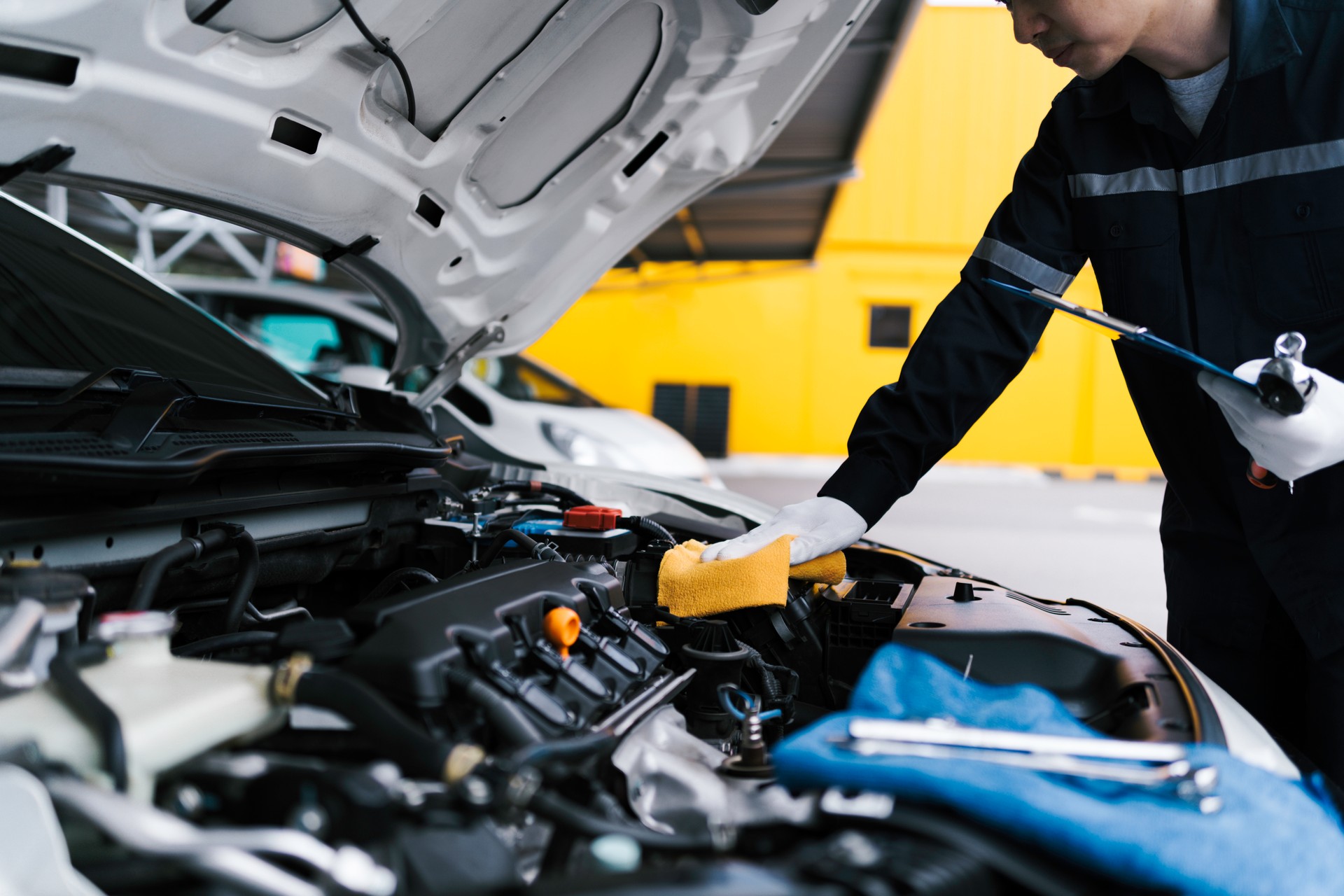 Automobile mechanic repairman checking a car engine by inspecting and writing to the clipboard the checklist for repair machine and car service for maintenance and maintenance check concept.